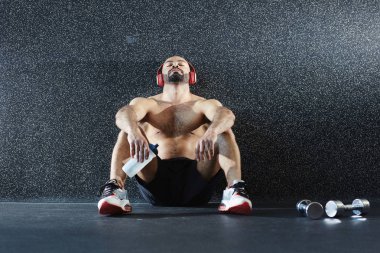 Genç atlet ise katta oturan ve kulaklık müzik dinlemek duvara yaslanmış