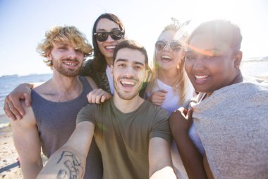 Çok etnik gruptan oluşan arkadaş selfie güneşli günde deniz kenarında yapma.