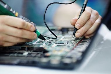 Elektrik akımı devre kartı sökülüp laptop bakım salonu tablo multimetre aracını kullanarak test eller closeup çekim