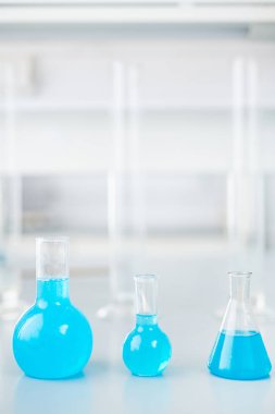 Üç cam şişeler renkli kontrollerimiz sıvı test araştırma modern laboratuvar masada hazır ile satır