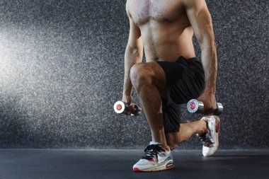 Gömleksiz adam yerdeki dumbbells ile egzersiz