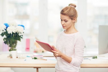Kadın çiçekçi yazılı e-posta için ona müşteri dururken geniş stüdyo panoramik pencere karşı konsantre