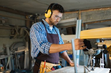 Yakışıklı sakallı woodworker önlük üzerinde dikey, bel çalışmaya başlamadan önce kalıpçı hızını ayarlama