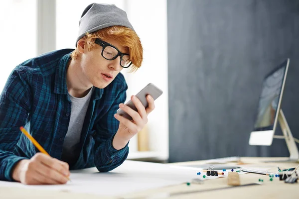 Retrato Jovem Criativo Homem Ruivo Inclinado Mesa Usando Smartphone Enquanto — Fotografia de Stock