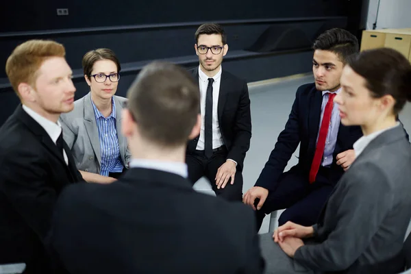 Business people sitting in circle and having discussion