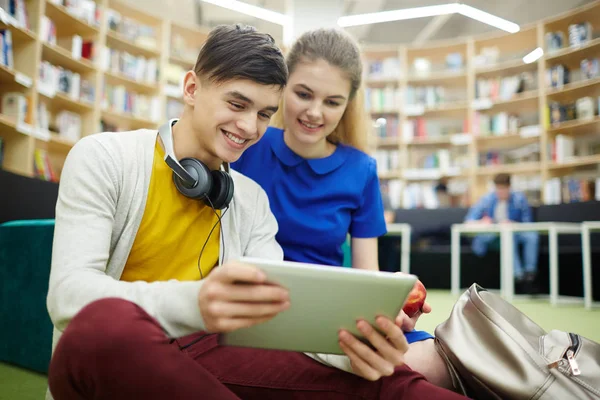 笑顔の学生カップル 少年と少女 大学図書館のラウンジで画面を見てデジタル タブレットを使用しての肖像画 — ストック写真