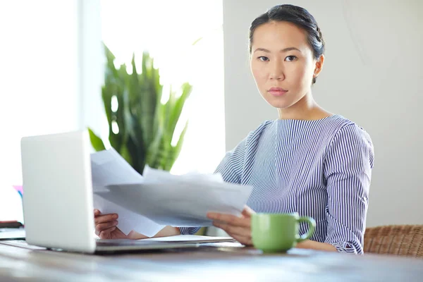 Portrait of young Asian woman dressed in casual clothe, working with laptop in modern office looking seriously at camera