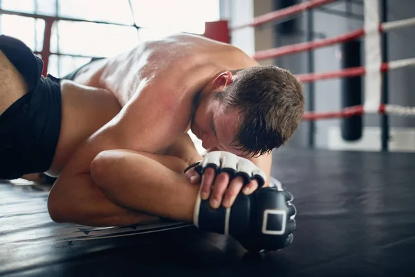 Portrait of shirtless sweaty wrestler fighting in boxing ring: tackling opponent with throw down and locking him
