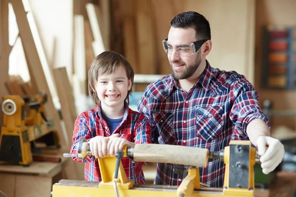 Szczęśliwy Chłopiec Ogląda Aparatu Przez Maszyny Drewna Ojcem Pobliżu Przez — Zdjęcie stockowe