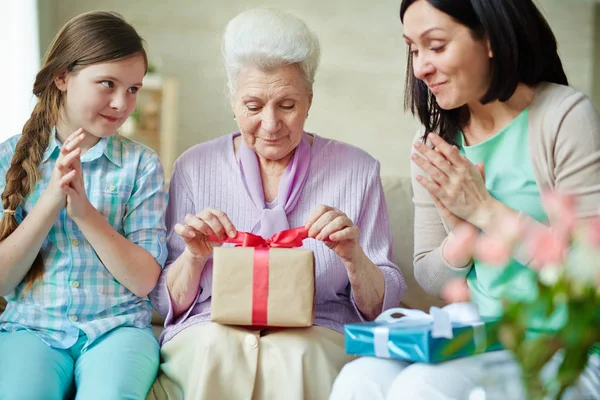 Girl Her Mother Clapping Hands While Aged Woman Opening Gift — Stock Photo, Image