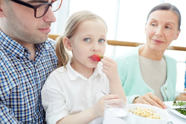 Söt Flicka Äter Jordgubbar Med Hennes Far Och Mormor Nära — Stockfoto