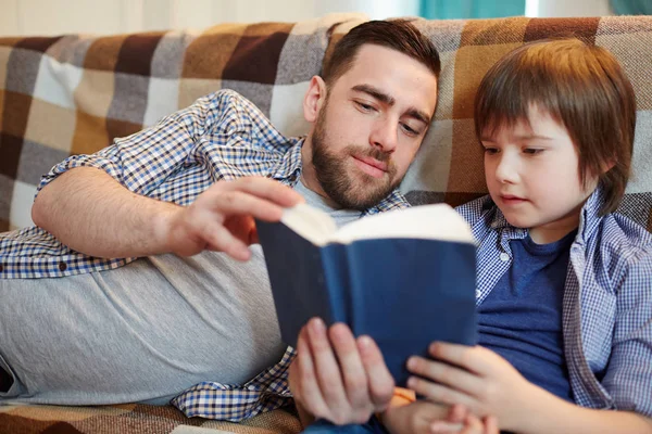 父と息子は ソファでリラックスしながら本を読んで — ストック写真