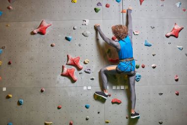 Genç sporcunun sıkı ipte asılı duvar tırmanma arka görünümü