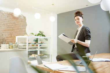 Kendine güvenen Manager'da genç kafede masada otururken belgesinde notlar yapma akıllı gündelik giysiler