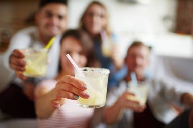 Bardak soda ya da ev yapımı kokteyl plastik saman ile genç kadın tarafından sırasında arkadaş parti düzenledi.