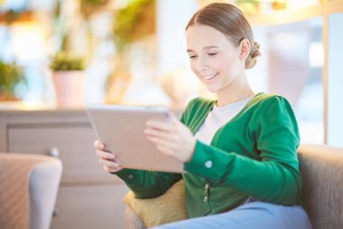 Boş olarak dinlenirken Web yayını izlerken tablet ile gülümseyen kız