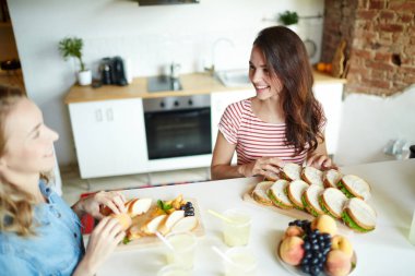 İki kız için onların arkadaşları mutfakta sandviç hazırlarken tablosuna göre söz