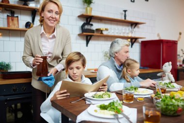 Sevimli çocuk onun kız kardeşi ve yakın dedesi tarafından sunulan tablo tarafından otururken kitap okuma
