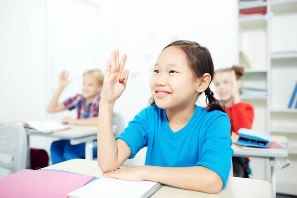 可爱的女学生和她的同学举手 而在课上工作 — 图库照片