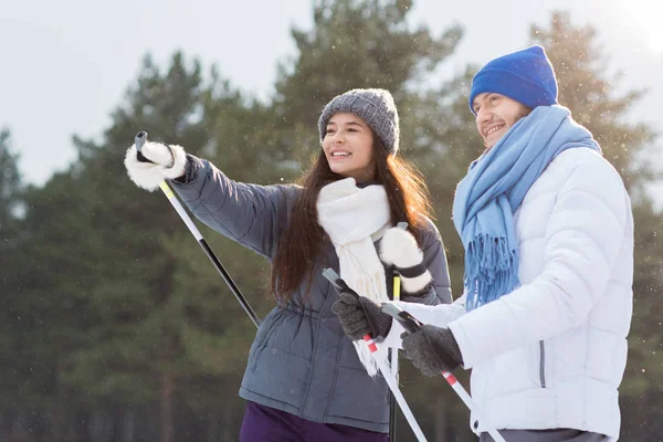 Young Female Skier Pointing Forwards While Showing Her Husband Good — Stock Photo, Image