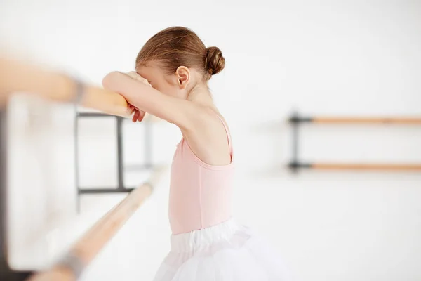 疲惫的小女孩倚在芭蕾教室的木酒吧训练后 — 图库照片