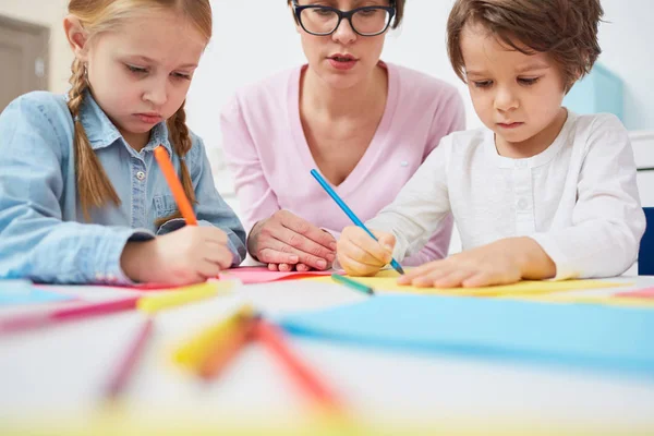 Entzückende Grundschüler Zeichnen Mit Buntstiften Auf Zetteln Dazwischen Der Lehrer — Stockfoto