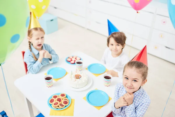可爱的小女孩和男孩坐在幼儿园的生日表和乐趣 — 图库照片