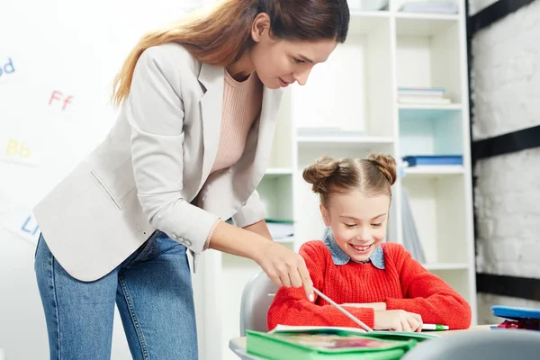 Joven Profesor Apuntando Nota Copybook Mientras Explica Algo Colegiala — Foto de Stock