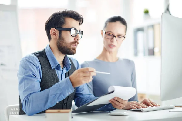 Bärtiger Finanzier Mit Dokument Das Auf Den Monitor Zeigt Während — Stockfoto