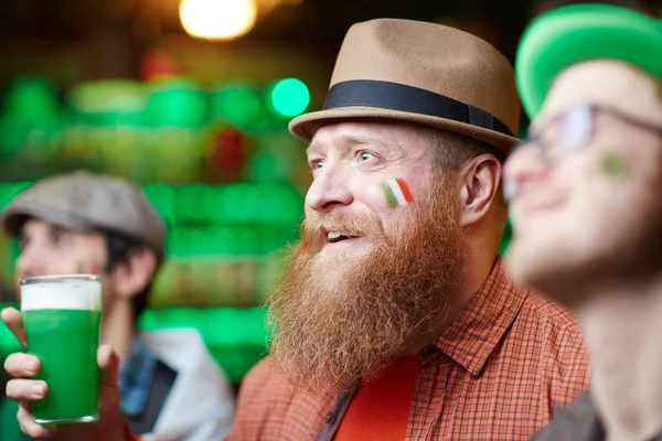 有胡子的男子与玻璃泡沫啤酒和他的朋友欢呼他们最喜欢的足球队在酒吧 — 图库照片