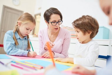Gösterilen ve açıklayan anaokulu öğretmeni nesneleri çizmeyi çocuklar