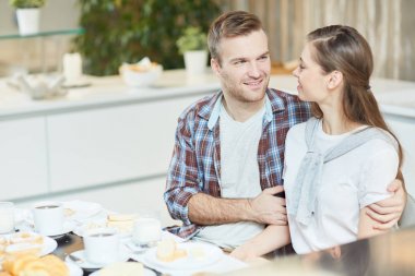 Genç çift başka bir mutfakta kahvaltı sırasında konuşurken arıyorsunuz