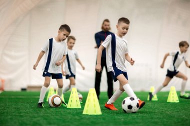Etkin çocuklar topları tarafından futbol koniler yeşil alan üzerinde çalışırken ile Tekdüzen eğitim