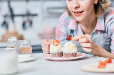 Üst kısmında hizmet öncesi sırlı Frenk üzümü ile cupcake dekorasyon pudra