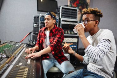 Dilim pizza sesler panosundaki karıştırılarak meslektaşı ile plastik bardaktan kahve içme ile genç adam