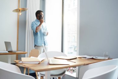 İşadamı ise ofis pencere tarafından ayakta ve içinden arıyorum smartphone tarafından arama çay ile