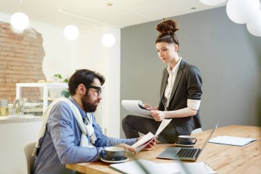 Genç kadın patron okuma kontratı veya diğer işletme belgesi kafede toplantısında dinlerken notlar yapma