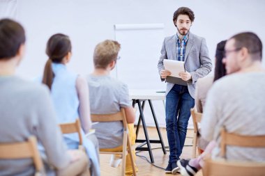 Kendine güvenen genç adam ya da çalıştırıcı ile not etmek onun deneyim paylaşımı sırasında hedef kitleye konuşuyor