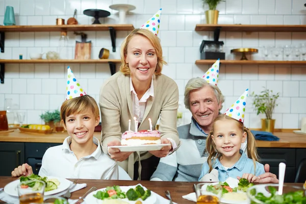 自宅で休日を祝う誕生日キャップの孫と祖父母 — ストック写真
