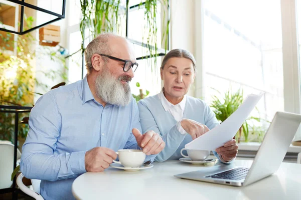 Два Зрелых Бизнесмена Сидят Столом Кафе Перед Ноутбуком Обсуждают Бумагу — стоковое фото