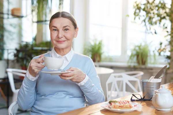 Lachende Volwassen Vrouw Met Kopje Thee Zitten Bij Tafel Genieten — Stockfoto