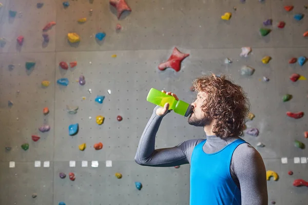 アクティブな男は クライミングの壁の背景にペットボトルから水を飲む — ストック写真