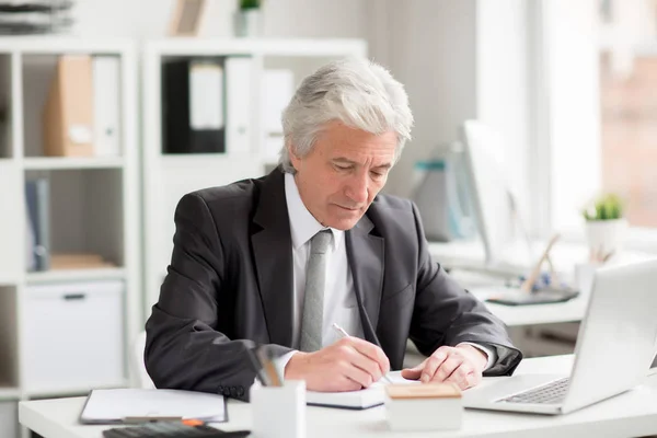 Senior Geschäftsmann Macht Sich Notizen Notizbuch Während Büro Arbeitsplatz Sitzt — Stockfoto