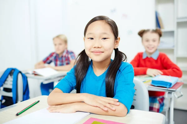 Niña Diligente Sentada Junto Escritorio Con Dos Compañeros Clase Fondo —  Fotos de Stock