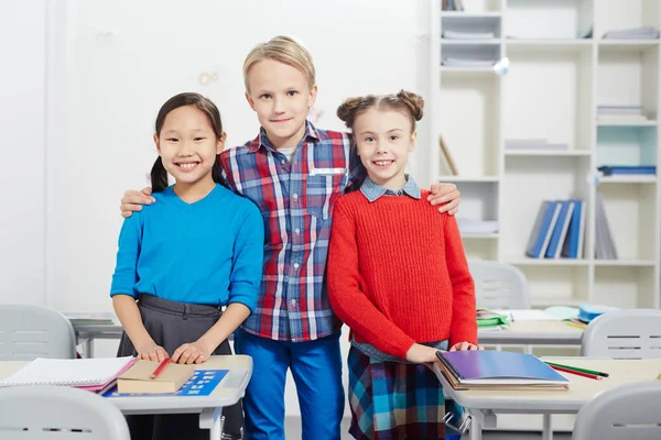 Young Boy Embracing Two Intercultural Classmates Classroom — Stock Photo, Image