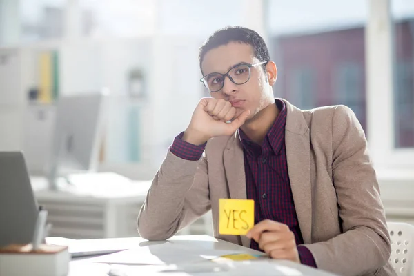 Sério Jovem Elegante Homem Sentado Lado Mesa Mostrando Papel Nota — Fotografia de Stock