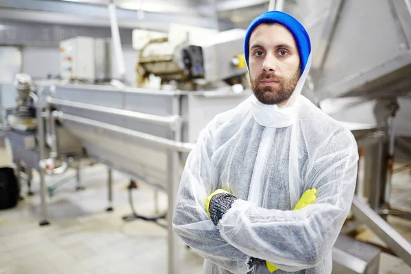 Serious young staff of seafood production factory looking at camera by workplace