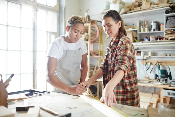 Dos Hembras Jóvenes Midiendo Tablón Madera Taller Contemporáneo —  Fotos de Stock