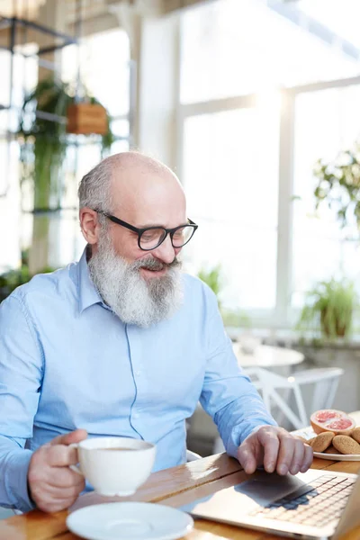 Seniorchef Mit Brille Sitzt Café Trinkt Tee Und Surft Netz — Stockfoto