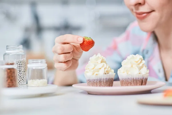 カップケーキのクリームのトッピングを食欲をそそる新鮮なイチゴをかぶる女 — ストック写真